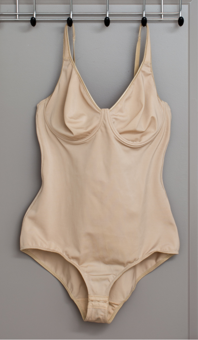 Beige swimsuit hanging on a rack against a gray background
